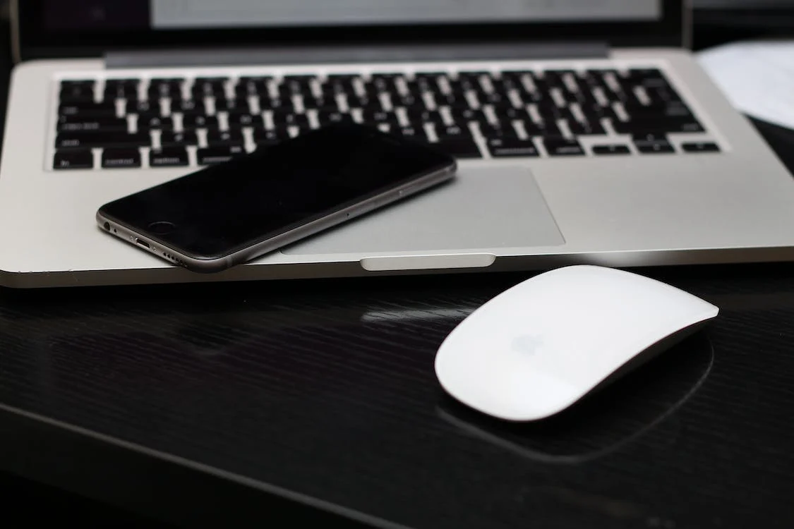 A laptop, a phone, and a wireless computer mouse