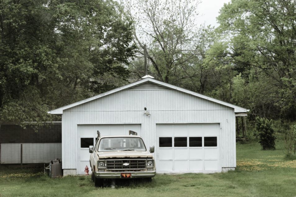 classic-white-chevrolet-pickup-truck-near-white-2-door-garage-near-trees