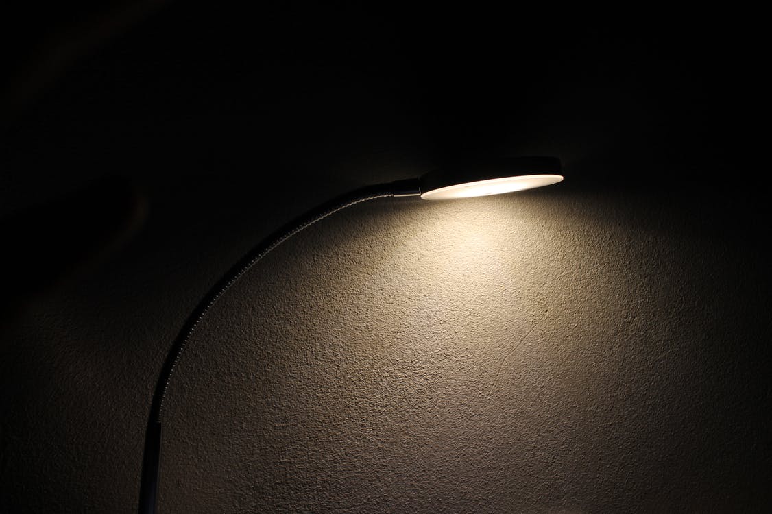 A slim, modern lamp shining in a dark room.