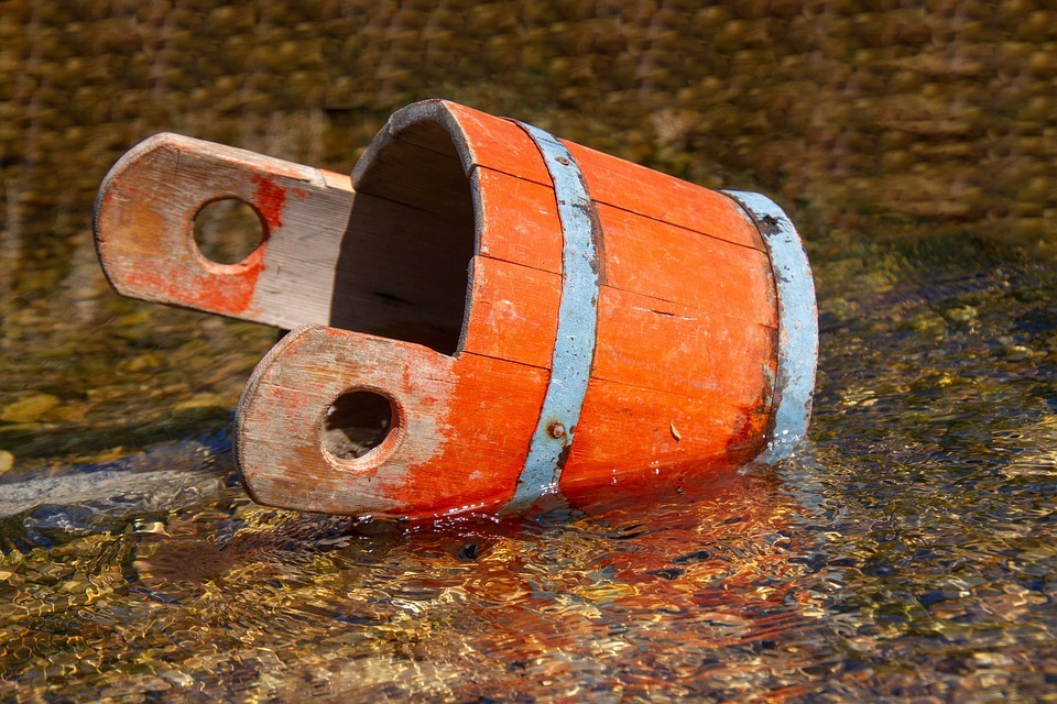 A wooden bucket lying on wet soil