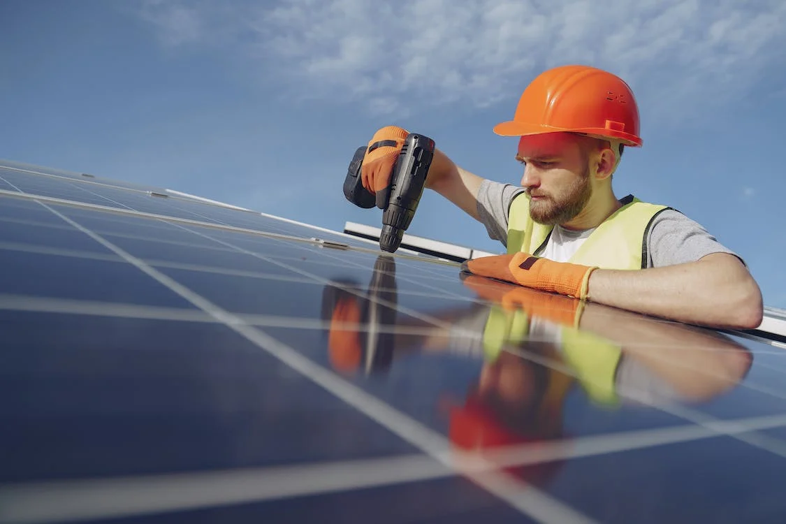man using an impact driver on a solar panel